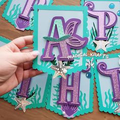 someone is holding up some cut outs to make their name cards for mermaid themed birthdays