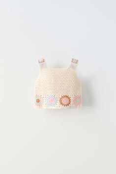 a crocheted purse with flowers on the front and shoulder, hanging from a hook