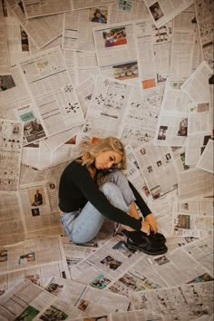 a woman sitting on the floor surrounded by newspapers