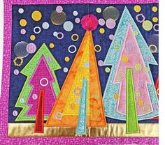 a quilted wall hanging with colorful christmas trees on it's side and bubbles in the background