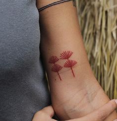 a woman's wrist tattoo with three red flowers on the left side of her arm