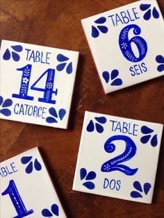 four blue and white ceramic table numbers on a wooden table