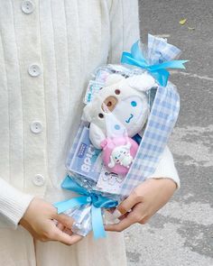 a person holding a teddy bear and other items in their hands while wearing a white sweater