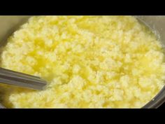 a bowl filled with yellow food next to a spoon