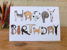 a birthday card with cats on it sitting on a table next to a potted plant