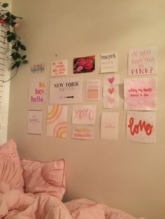 a bedroom with posters on the wall and pink bedding in front of it's window