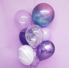 several balloons are arranged on a pink surface with glitters and sparkle balls in the middle