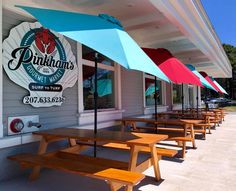 the outside of a restaurant with picnic tables and umbrellas on the side of it