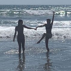 two people standing in the ocean holding hands