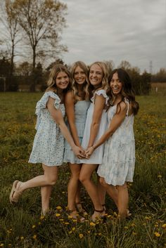 three girls standing together in a field with their arms around each other and smiling at the camera