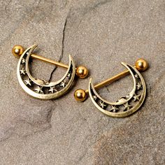 two pairs of gold toned earrings with stars and moon designs on them sitting in the sand