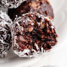 chocolate truffles on a white plate with coconut flakes and powdered sugar