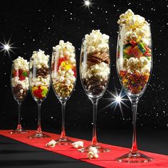 five wine glasses filled with different types of candy and candies on a red table