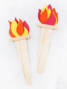 two popsicle sticks with flames on them sitting next to each other in front of a white background