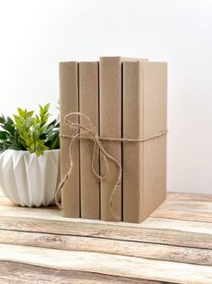 two wrapped gift boxes sitting on top of a wooden table next to a potted plant