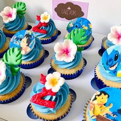 cupcakes decorated with blue frosting and flowers are displayed on a white table