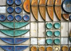 several different shapes and sizes of glass on a tile wall with blue, green and brown colors