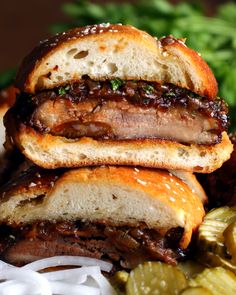 three sandwiches stacked on top of each other next to some pickles and bread slices