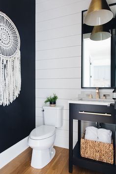 a white toilet sitting next to a sink in a bathroom under a hanging dream catcher