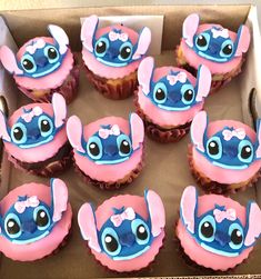 there are many cupcakes in the box with blue and pink frosting on them