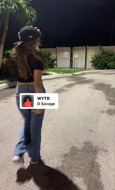 a woman is walking down the street at night with her shadow on the ground and palm trees in the background