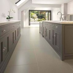 a large kitchen with white walls and flooring has skylights above the countertops