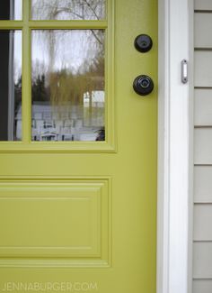 a yellow front door with black knobs and two glass panes on the side