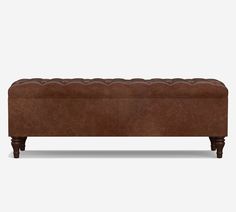 a brown leather bench with wooden legs