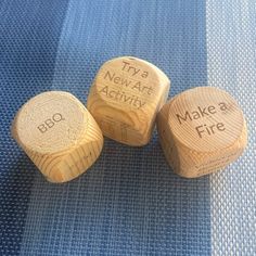 three wooden dices with writing on them that say do, try and make a fire