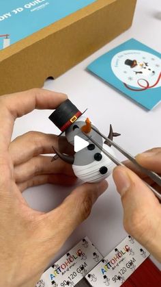 a person is making a snowman out of paper and scissors on a white table