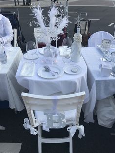 the table is set with white linens and silverware for an elegant dinner party