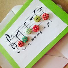 a birthday card with buttons on it and music notes in the background, sitting on top of an envelope