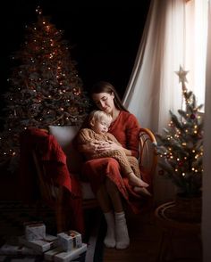 a woman and child sitting in front of a christmas tree