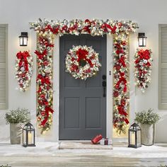 a front door decorated for christmas with wreaths and decorations on the outside, along with two lanterns