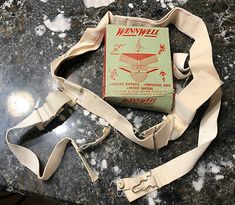 an old manual book sitting on top of a marble table next to a white strap