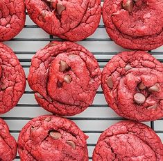 red cookies with chocolate chips are cooling on a wire rack in front of the camera