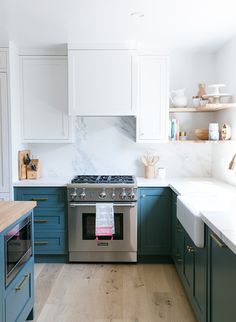 a kitchen with blue and white cabinets, an oven and counter tops in the center