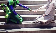 two people dressed in costumes sitting on some steps and one is pointing at the other