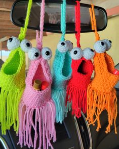 four crocheted stuffed animals hanging from a car dash board with colorful yarns