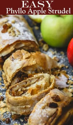 an apple and cinnamon roll cut in half on top of a table with apples behind it