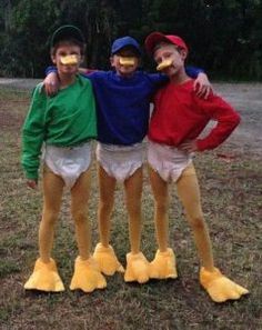 three young boys dressed up as ducks posing for a photo in front of some trees