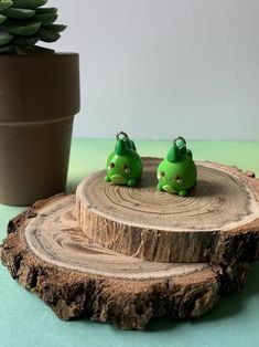 two little green birds sitting on top of a tree stump