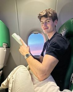 a man sitting on an airplane reading a book