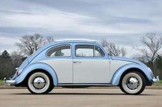 an old blue and white car is parked on the street