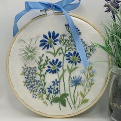 a blue ribbon is hanging on a white wall next to a vase with purple flowers