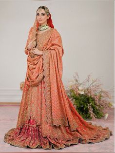 a woman in an orange and red bridal gown standing with her hands on her hips