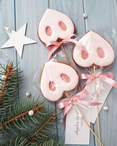 cookies decorated with pink icing and bows on top of a blue wooden table next to a christmas tree