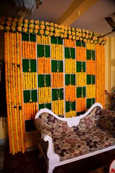 a couch sitting in front of a green and yellow wall with orange flowers on it