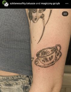 a woman with a tattoo on her arm holding a cup and saucer in front of her