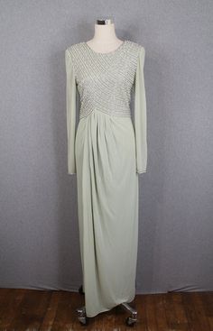 "Description: - This 1970s, 1980s beaded evening gown is absolutely stunning - It is a soft sage green, very subtle green - Beautiful pearl beading and translucent beading on the bodice and wrists - Sheer sleeves - Flattering drape detail from the bodice to the skirt - Zipper up the back - Shoulder pads - Made in Hong Kong by Victoria Condition: - This dress is in beautiful condition - All beading is in tact - There is one faint spot on the bodice, but we have not yet treated it (see video) - Th Fitted Beaded Evening Dress, Beaded Floor-length Mother Of The Bride Evening Dress, Evening Gown With Beaded Fitted Bodice, Fitted Beaded Evening Gown, Fitted Beaded Gown For Evening, Beaded Floor-length Evening Gown, Beaded Fitted Maxi Dress For Evening, Fitted Beaded Maxi Dress For Evening, Formal Cocktail Party